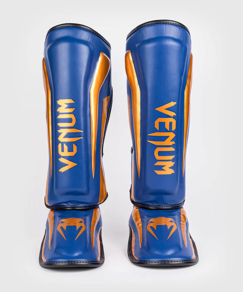 Paratibie Venum Elite Blu Royal e Oro realizzati a mano in Thailandia garantiscono protezione e comfort di livello professionale per i tuoi allenamenti di Muay Thai, MMA e Kickboxing. Design avvolgente e ultraleggero per la massima mobilità.