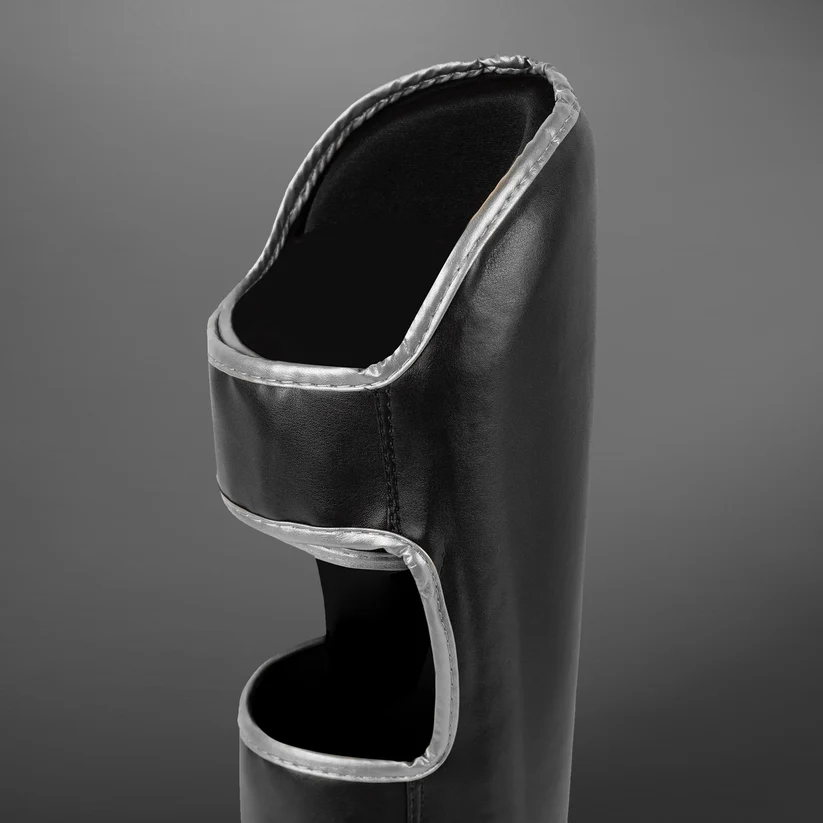 Paratibie Venum Chllenger Nero/Silver VENUM-2050-128 per allenameti di Muy Thai, kickboxing ed MMA. Paratibie strutturato da allenamento con chiusura in velcro stabile e solido, Paratibie principianti.