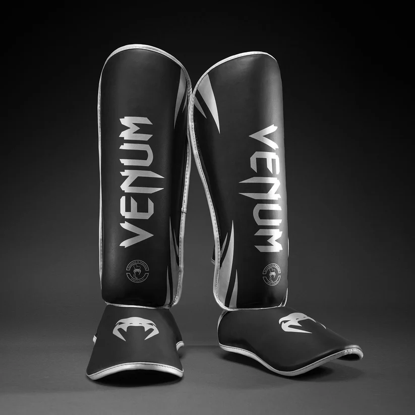 Paratibie Venum Chllenger Nero/Silver VENUM-2050-128 per allenameti di Muy Thai, kickboxing ed MMA. Paratibie strutturato da allenamento con chiusura in velcro stabile e solido, Paratibie principianti.