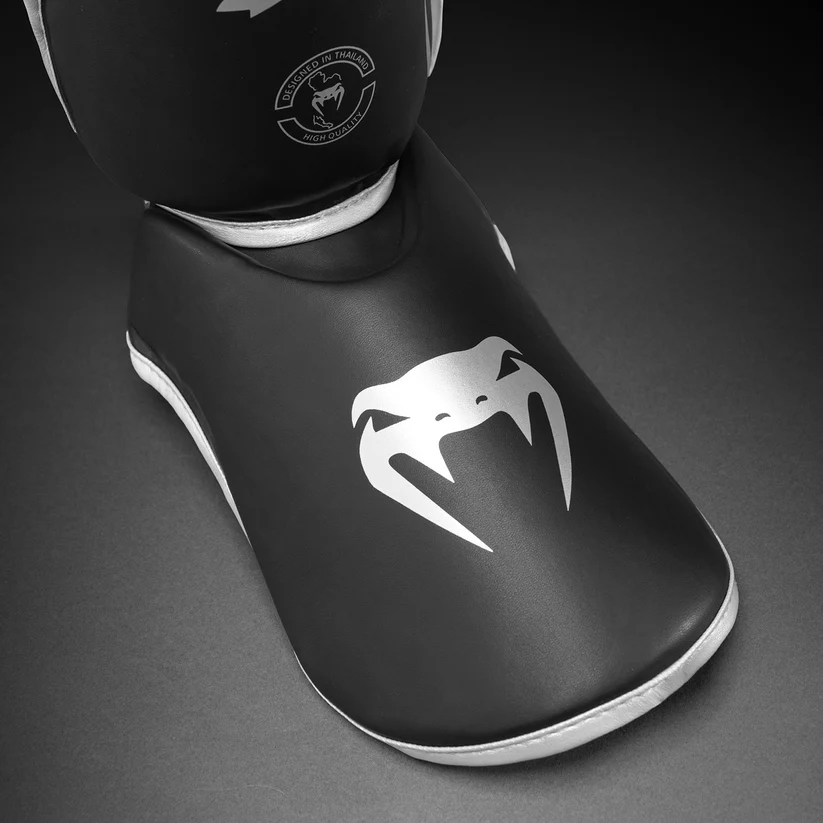 Paratibie Venum Chllenger Nero/Silver VENUM-2050-128 per allenameti di Muy Thai, kickboxing ed MMA. Paratibie strutturato da allenamento con chiusura in velcro stabile e solido, Paratibie principianti.